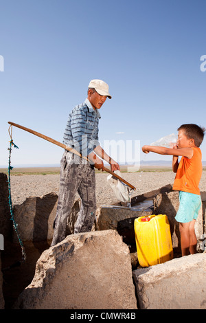Padre e figlio bail il bene acqua nel deserto dei Gobi, Mongolia Foto Stock
