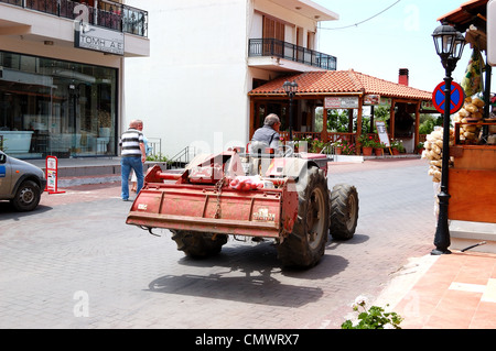 Occupato agricoltore greco aziona il suo trattore attraverso il villaggio di Spili, Creta, Grecia Foto Stock