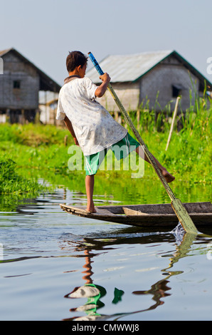 Giovane ragazzo in barca a remi in modo tradizionale, Lago Inle, Myanmar Foto Stock