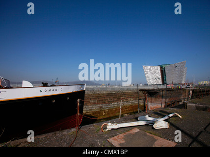 La nave nomadi si siede nel bacino di carenaggio con il Titanic Visitor Centre in background in Belfast, Irlanda del Nord Foto Stock