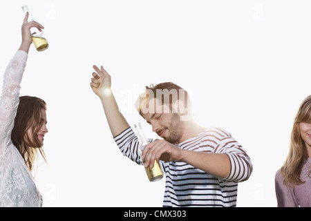 Germania, Colonia, giovane uomo e donna ballando con le bottiglie di birra, sorridente Foto Stock