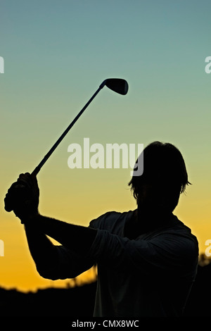 Il Golfer stagliano tramonto nella metà del backswing con ferro. Foto Stock