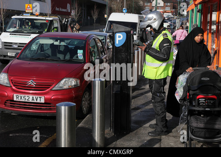 Un vigile emette un biglietto per una vettura parcheggiata illegalmente. Wembley, Londra Foto Stock