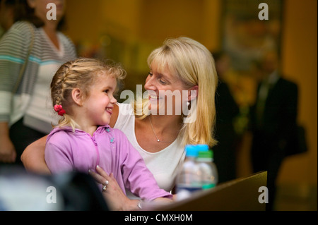 Madre e figlia insieme sorridente in Heathrow airport lounge di partenza Foto Stock