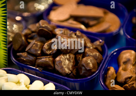 Decadente cercando cioccolato candy eccitante e collocata in un vassoio blu accanto ad altri dolciumi dolce selezioni in un mercato alimentare. Foto Stock