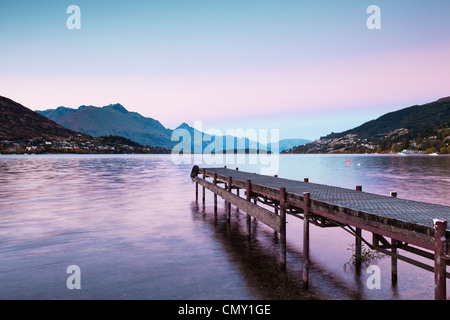 Un vecchio molo sulle rive del lago Wakatipu, Queenstown, Otago, Nuova Zelanda, e Queenstown in distanza. Foto Stock