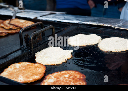 Alcuni finiti e non le frittelle su un grill in attesa di essere serviti. Foto Stock