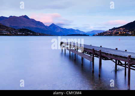 Un vecchio molo sulle rive del lago Wakatipu, Queenstown, Otago, Nuova Zelanda, e Queenstown in distanza. Foto Stock