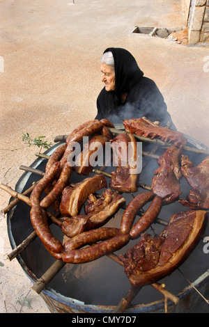 Una vecchia signora Maniat dal villaggio Dryalos, è la preparazione di 'syglino' (noto anche come "pasto'=affumicato di maiale) e salsicce. Mani, Grecia. Foto Stock