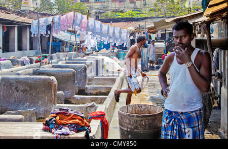 Dhobi Ghat, Mumbai, uomini al lavoro con uomo meditando su cosa fare la prossima Foto Stock