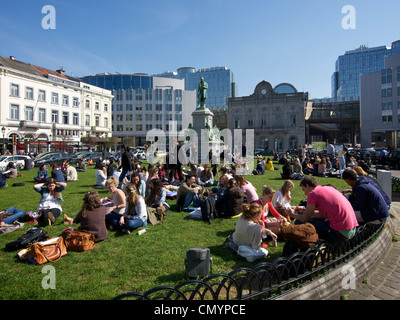 Molte persone per godersi il sole durante la pausa pranzo sul prato del Place du Luxembourg a Bruxelles, in Belgio Foto Stock