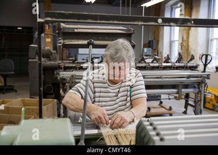 Lavoratore opera un telaio presso la storica Amana Wollen Mill Foto Stock