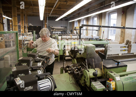 Lavoratore opera un telaio presso la storica Amana Wollen Mill Foto Stock