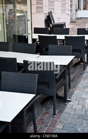 Bianco vuoto tavoli e sedie nere al di fuori di un ristorante cafe. Foto Stock