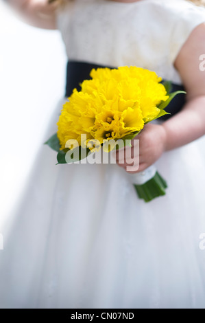 Ragazza in un abito bianco tenendo un mazzetto di daffodil Foto Stock