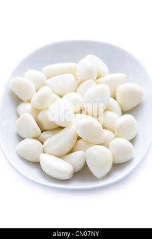 Sbucciate decapati spicchi di aglio in un piatto su sfondo bianco Foto Stock