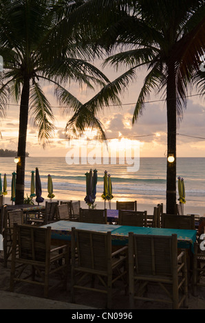 Palme silhouette oltre a lato della spiaggia di tavolo e sedie, Kamala Beach, Phuket, Tailandia Foto Stock