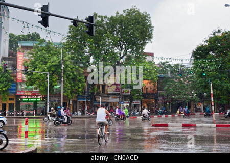 Ciclisti e motociclisti ciclomotore in una tempesta di pioggia Hanoi, Vietnam Foto Stock