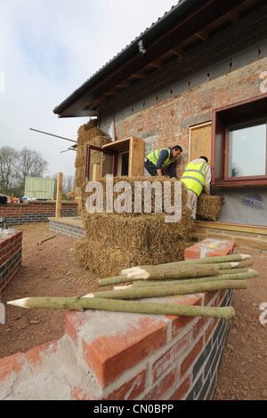 I costruttori utilizzano la paglia per l'isolamento su un nuovo eco-friendly building Foto Stock