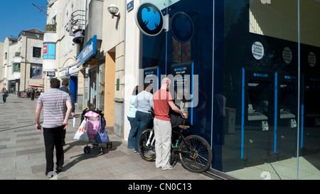 Un uomo con una bicicletta il prelievo di denaro da una banca Barclays ATM Hayes Galles Cardiff Regno Unito Foto Stock