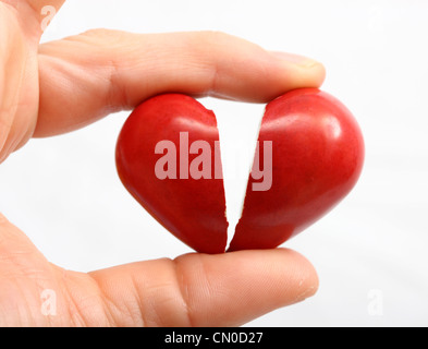 Immagine simbolica, malattie cardiache, infarto, protezione, prevenzione, cardiologia. Mani tenendo la rottura di un cuore rosso, in 2 pezzi. Foto Stock