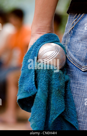 Un uomo è in possesso di un bocci palla in mano durante una partita a Luang Prabang, Laos. Foto Stock