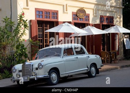 Un classico Mercedez Benz automobile è parcheggiata di fronte 3 Nagas ristorante su una strada di città a Luang Prabang, Laos. Foto Stock