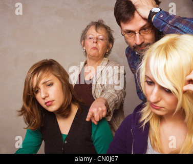 Due ragazze teenager facendo il loro dovere insieme con i loro genitori Foto Stock