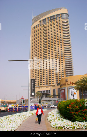 Una donna in una giacca rossa in alto di fronte all'indirizzo Hotel, Centro commerciale di Dubai, Dubai, Emirati Arabi Uniti Foto Stock