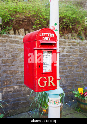 Rosso brillante post box attaccato ad un bianco decorato e dipinto lampione a Frome Somerset inscritto GR (George Rex) per George V Foto Stock