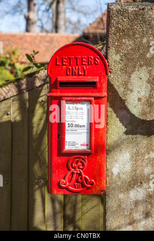 Rosso brillante post box attaccato ad un bianco decorato e dipinto lampione in Surrey inscritto ER VII (Edward Rex), Edward VII Foto Stock