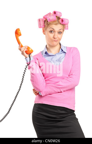 Una giovane donna con i capelli rulli tenendo un retrò tubo di telefono isolato su sfondo bianco Foto Stock