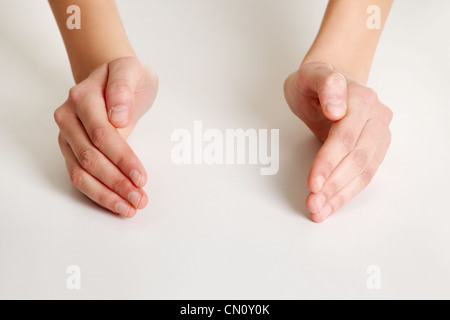 Mani femminili in forma di protezione su una scrivania bianca Foto Stock