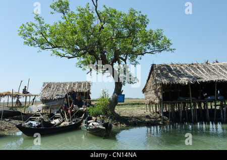Capanne di bambù e barche lungo una via navigabile. Delta di Irrawaddy. Myanmar. Foto Stock
