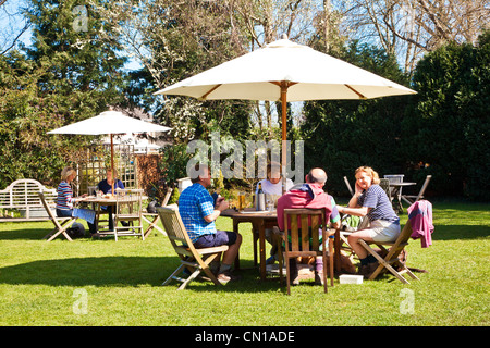 Persone in chat, mangiare e bere in un pub giardino nel sole di primavera nel Wiltshire, Inghilterra, Regno Unito Foto Stock