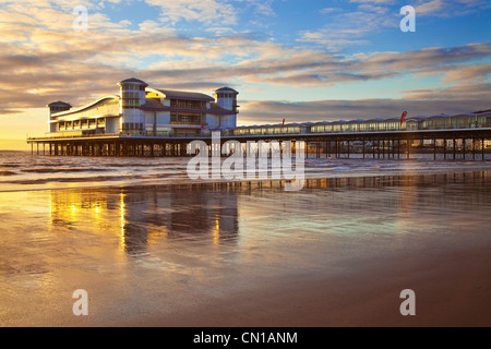 Golden luce della sera cade sul grande molo Weston-Super-Mare, Somerset, Inghilterra, Regno Unito eflected nella sabbia bagnata a marea alta. Foto Stock