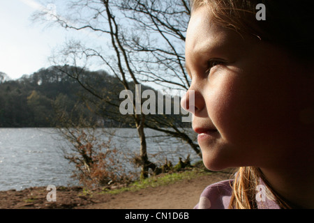 Ragazza seduta su un treno si affaccia sul lago e il paesaggio Foto Stock