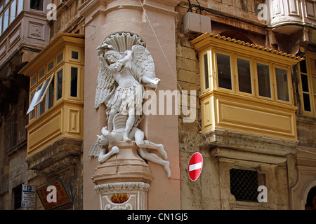 Fregio statua di San Michele e il diavolo su edifici con terrazze coperte a La Valletta, Malta Foto Stock