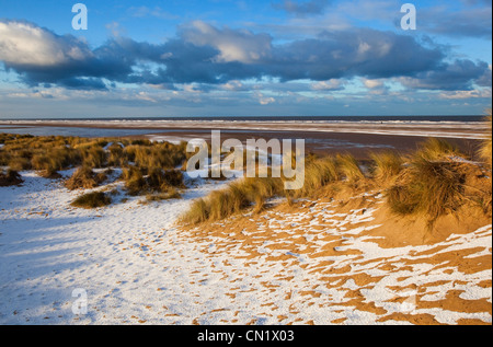 Neve che ricoprono le dune di sabbia e spiaggia a Holkham Bay sulla costa di Norfolk in inverno Foto Stock