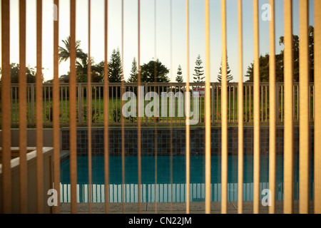 Vista della piscina attraverso le persiane della finestra Foto Stock