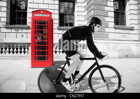 Ciclista pedalando attraverso il telefono rosso box Foto Stock