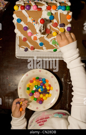 Ragazza giovane decorare gingerbread house Foto Stock