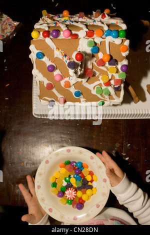 Ragazza giovane decorare gingerbread house Foto Stock