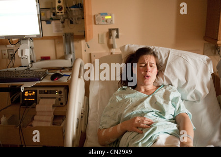 Donna incinta di manodopera sul letto di ospedale Foto Stock