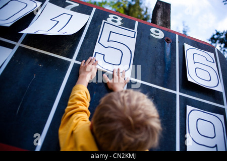 Giovane ragazzo giocando con i numeri sul tabellone Foto Stock