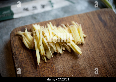 Fresche a fette di zenzero radice sul tagliere di legno Foto Stock