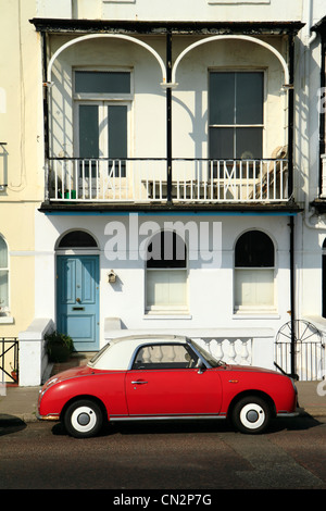 Red Nissan Figaro parcheggiato di fronte del XIX secolo in casa a schiera, St Leonards-on-Sea, East Sussex, Regno Unito Foto Stock