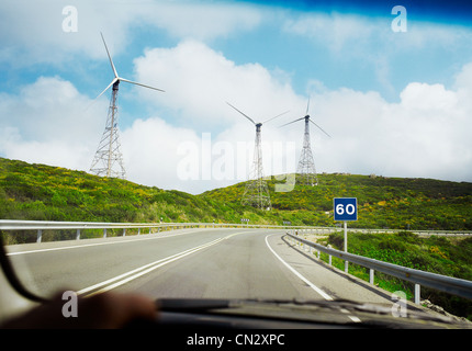 Vista di turbine eoliche e strada attraverso il parabrezza di automobile Foto Stock