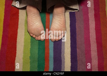 Bambino con i piedi sul tappeto a strisce Foto Stock