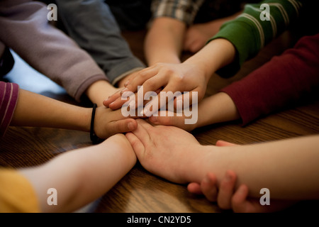 I bambini in huddle toccando le mani Foto Stock